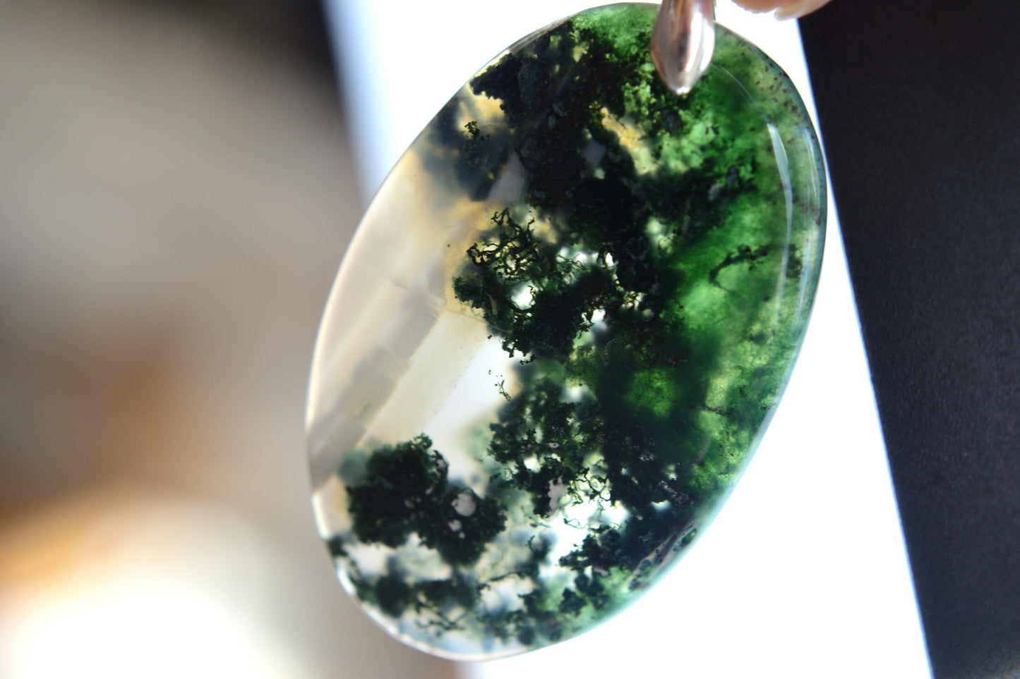 Close-up of a green and white marbled stone pendant on a blurred background